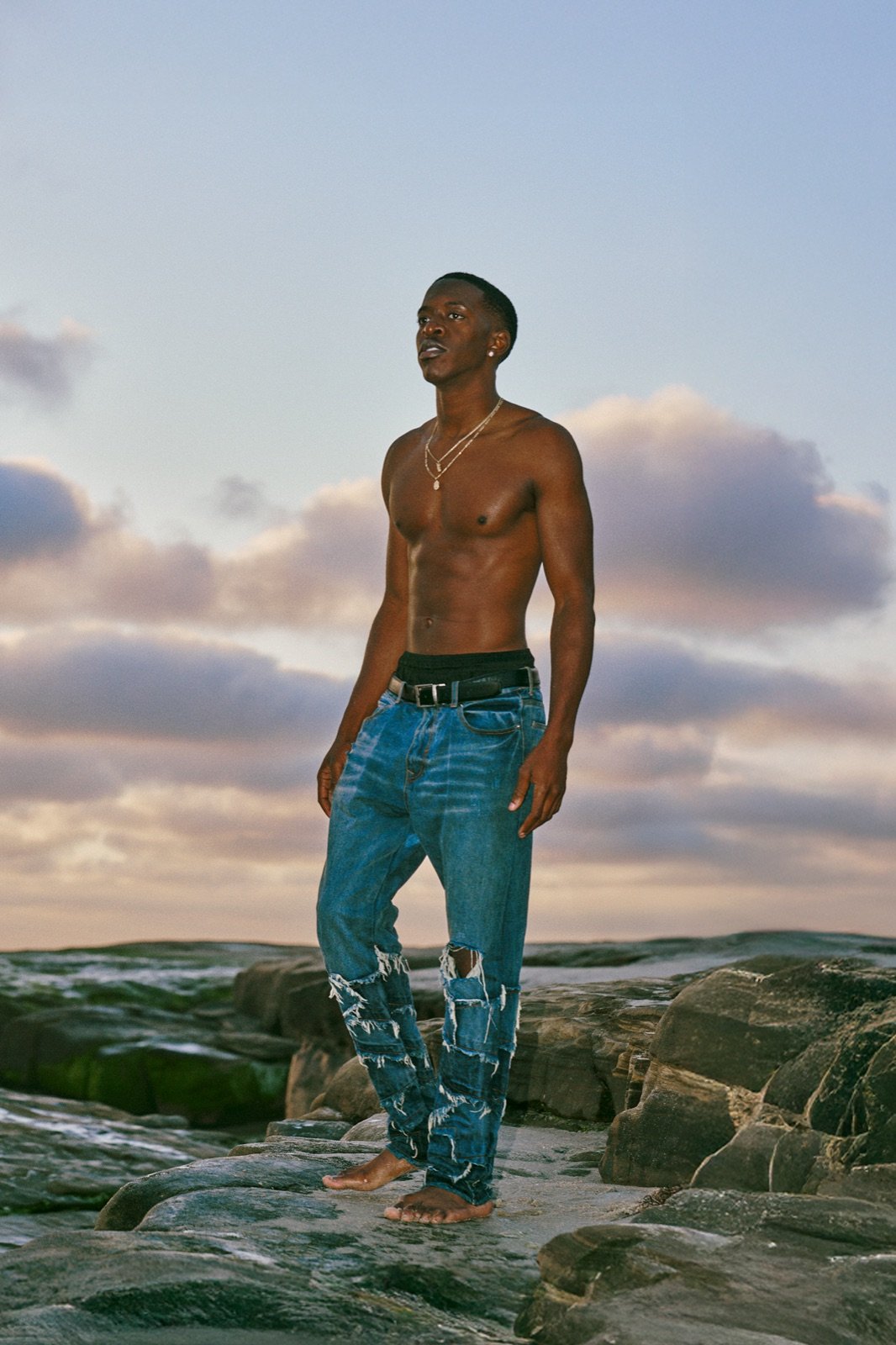 Ripped jeans, head back on the rocks